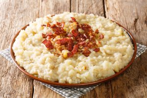 Homemade potato and barley mulgipuder with onion and bacon close-up in a plate.